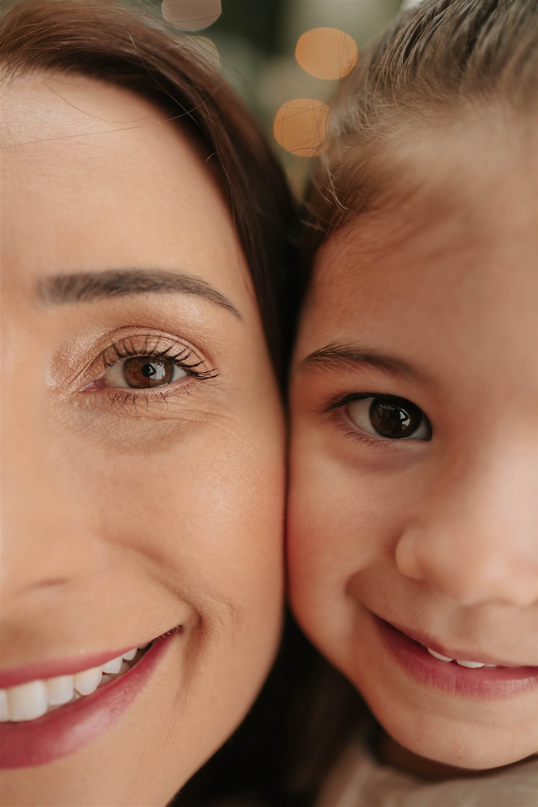 Retrato próximo de mãe e filha sorrindo, com os rostos juntinhos