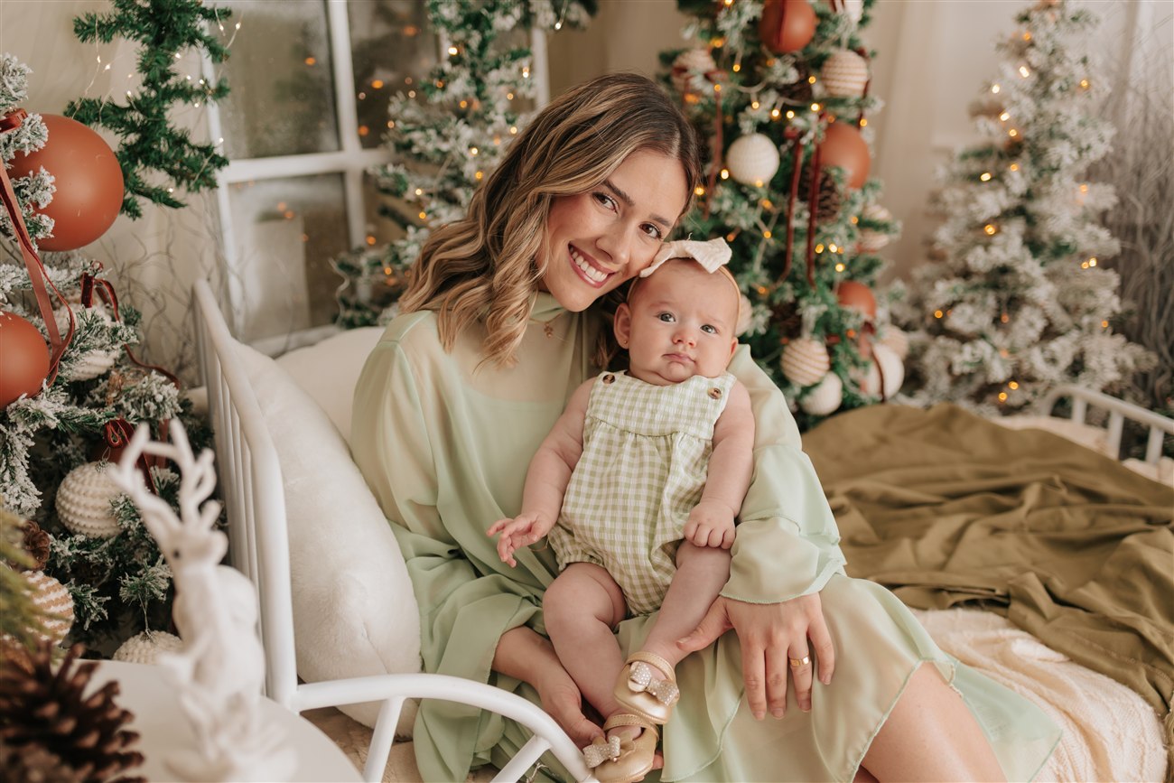 Mãe e sua pequena filha juntas, cercadas pelas luzes de Natal